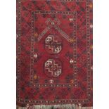 A small Persian rug with a geometric pattern upon a red ground, 110cm x 83cm