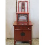 A small Chinese stained/lacquered side cupboard enclosed by a pair of doors beneath two frieze