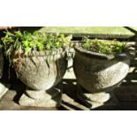 A pair of weathered composition stone oviform planters raised on square platform bases, 38 cm