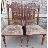 A set of four Edwardian Art Nouveau style walnut high back dining chairs with pierced and shaped
