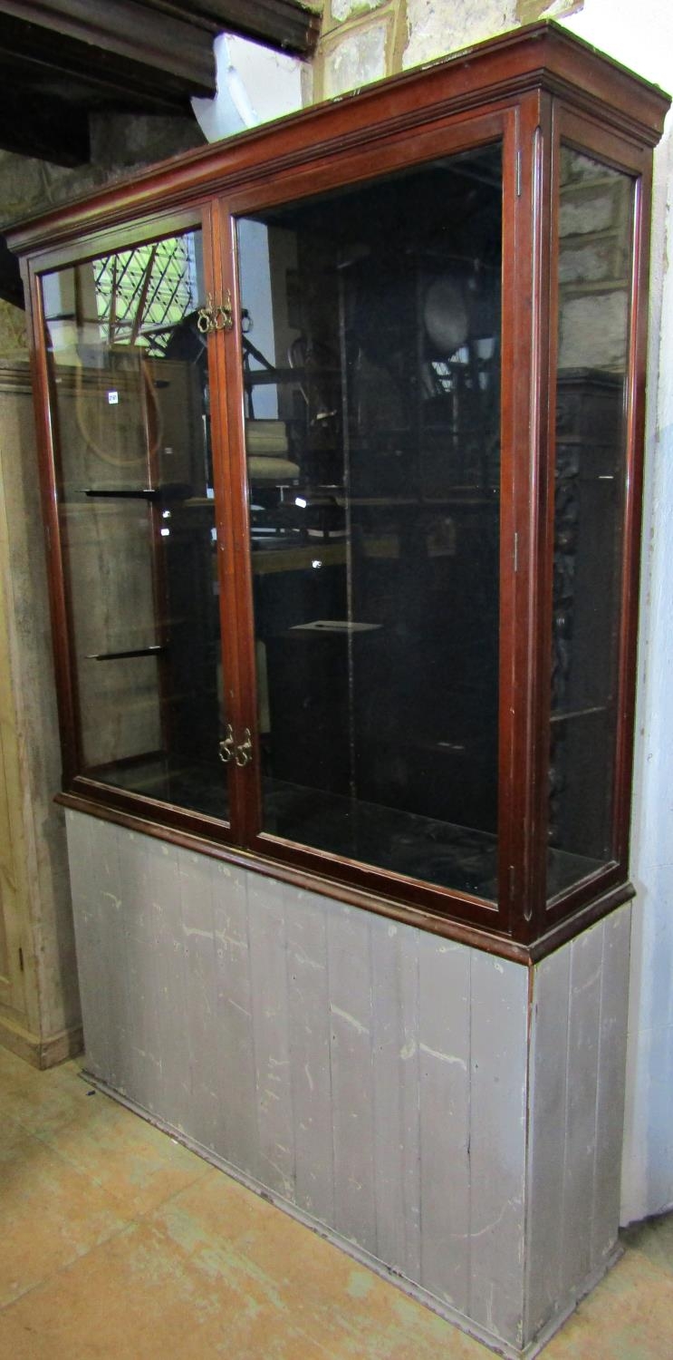 A vintage mahogany shop display cabinet with chamfered and moulded framework and enclosed by a