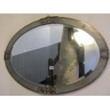 A 1920s mirror of oval form with simulated slated borders within a brass outer framework,