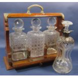An Edwardian oak tantalus with a pair of decanters and a third decanter with an all over hobnail