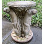 A weathered cast composition stone bird bath of circular form raised on three standing otter
