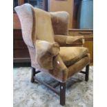 A Georgian style wing armchair with shaped outline moustache back raised on square cut and moulded