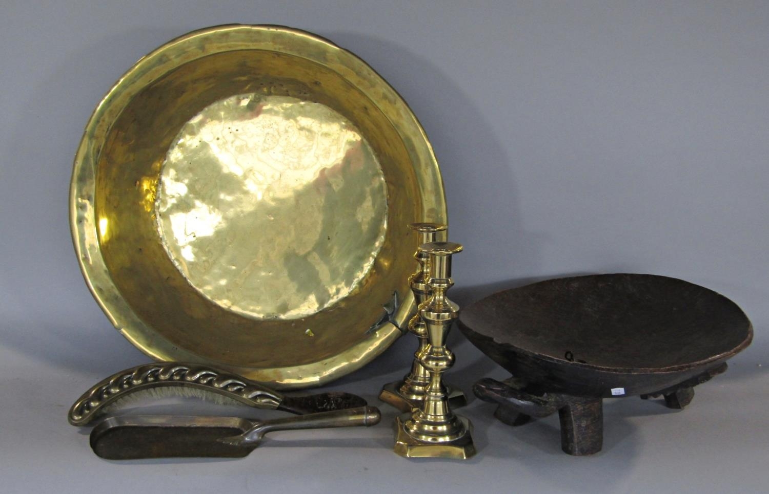 A brass metal basin (AF), a pair of brass candlesticks, brush and slide and a wooden tribal bowl