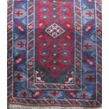 A Kazak style carpet with a central extended medallion with a blue, red and green colourway,
