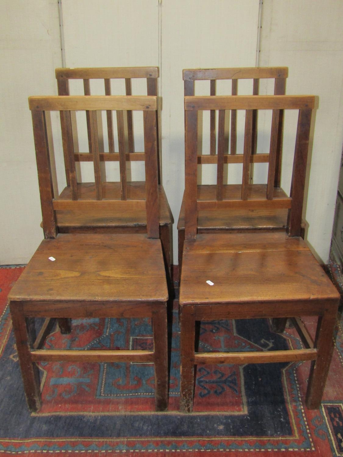 A set of four Georgian country made dining chairs with reeded stick backs over solid seats and