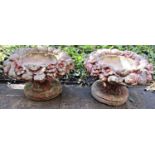 A pair of weathered cast composition stone planters of squat circular form with fruiting and