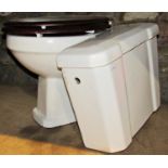 A white glazed ceramic toilet with chrome pipe and flush box cistern and fittings