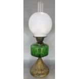 A 19th century oil lamp with a green glass font raised on a gold painted flared base. 56cm high.