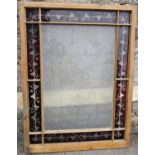 A reclaimed stripped pine framed window with repeating rectangular floral designed panel within a