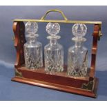 An Edwardian style tantalus with three cut glass decanters, with key.