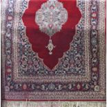 A modern hand knotted wool middle eastern design carpet with a central medallion upon a red