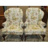A pair of Queen Ann style wing armchairs, with shaped and rolled outline, repeating floral patterned