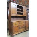 An oak dresser, the base fitted with a T shaped arrangement of six drawers flanked by arched