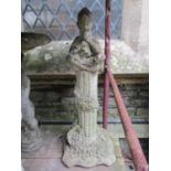 A weathered cast composition stone garden ornament in the form of Pan seated cross legged and
