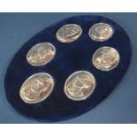 An oval blue velvet lined stand with six silver medallions of the Royal Family, celebrating the