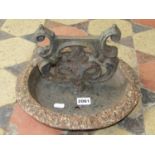 A cast iron boot scraper with scrolling foliate detail and circular dished tray base