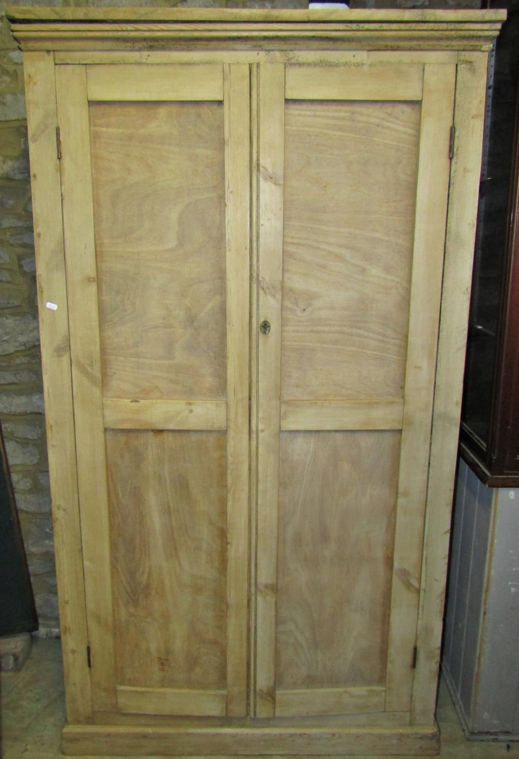 An antique stripped pine floorstanding side cupboard enclosed by a pair of full length plywood