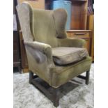 A Georgian style wing armchair, with shaped and rolled outline and upholstered finish, raised on