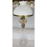 A Wesseners oil lamp with opaque white glass shade and clear cut glass font, supported by bronze and