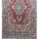 A middle eastern design carpet with a central floral medallion upon a red ground, 200cm x 140cm