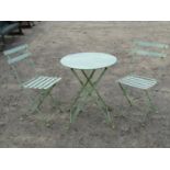 A light green painted folding light steel three piece bistro set comprising circular top table, 60