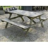 A weathered soft wood picnic table with fixed side benches, the top 150 cm long x 70 cm wide