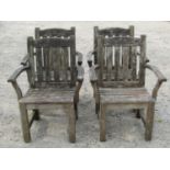 A set of four weathered teak garden open armchairs with slatted seats and backs beneath slightly