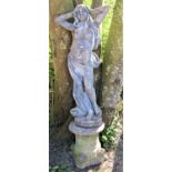 Weathered composition stone garden statue in the form of a standing scantily clad maiden, raised