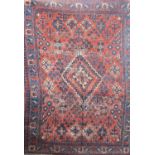 A Josheghan rug with a geometric pattern and stylised flowers on an orange ground. 190cm x 135cm