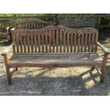 Good quality weathered teak three seat garden bench with slatted seat and back, beneath a shaped