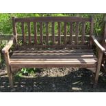 A weathered contemporary two seat garden bench with slatted seat and back, beneath a slightly arched
