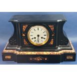 A Victorian black slate and polished marble mantle clock with shaped outline and enamel dial