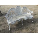 A decorative cream painted cast aluminium garden bench with serpentine outline and decorative