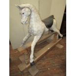 A carved timber dapple grey rocking horse raised on a central rocker, 110cm high approx max