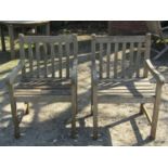 A pair of weathered teak garden open armchairs with slatted seats and curved slatted backs, 60cm