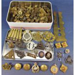 A tin containing military lapel badges, buttons, spent shells, etc