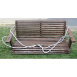 A stained teak two seat garden swing with slatted seat (rope hung) 133 cm wide