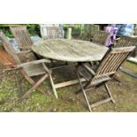 A weathered teak garden table with circular slatted top raised on x framed supports 150 cm in