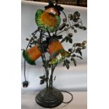An Art Nouveau style bronze effect lamp with grape vine detail and three amber and green floral