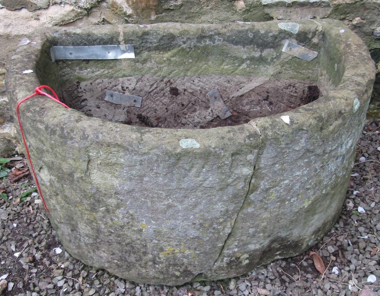 A weathered natural stone D shaped trough (broken and repaired but complete) 94cm wide