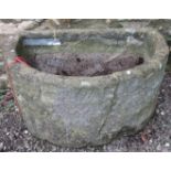 A weathered natural stone D shaped trough (broken and repaired but complete) 94cm wide