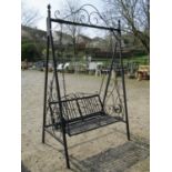 Ironwork two seat garden swing with strapwork seat, scrolled arms and detail, hung within square