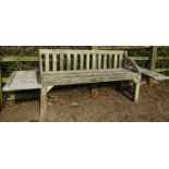 An unusual, weathered teak garden bench with slatted seat, back and arched arms, with later table
