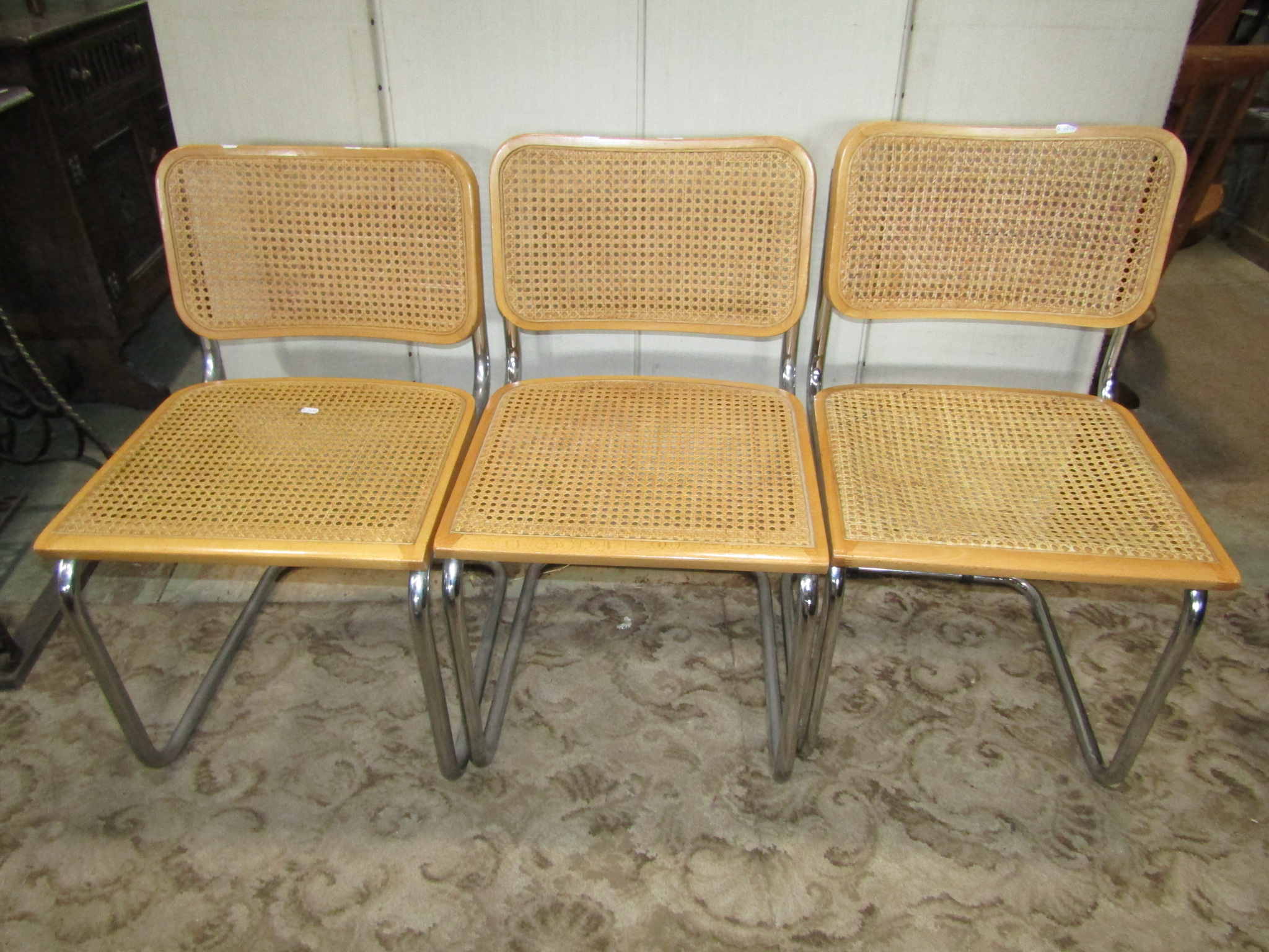 A set of three tubular framed cantilever dining chairs with cane panelled seats and backs