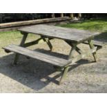 A weathered soft wood picnic table with fixed side benches, the top 150 cm long x 70 cm wide