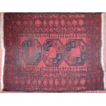 A small Turkamen rug with three medallions on a red ground. 110cm x 85cm