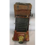 A Victorian wooden and brass folding bellows field camera with plates and original carrying bag. (